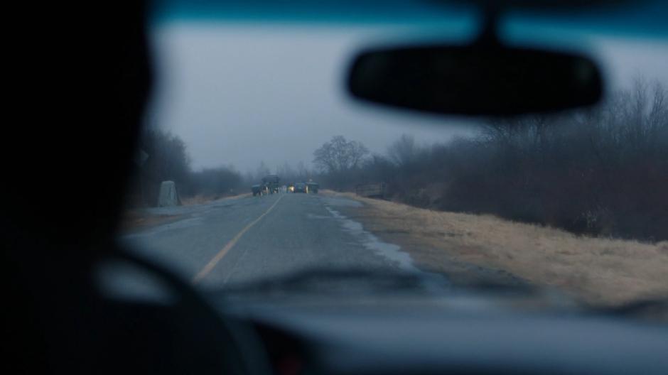 A military checkpoint sits in the road ahead of Ben and the others.