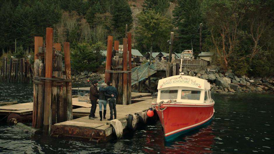 Xander, Janine, and Calvin walk back down the dock past the boat marked with "Captain Calvin's Mermaid Adventure Tours".