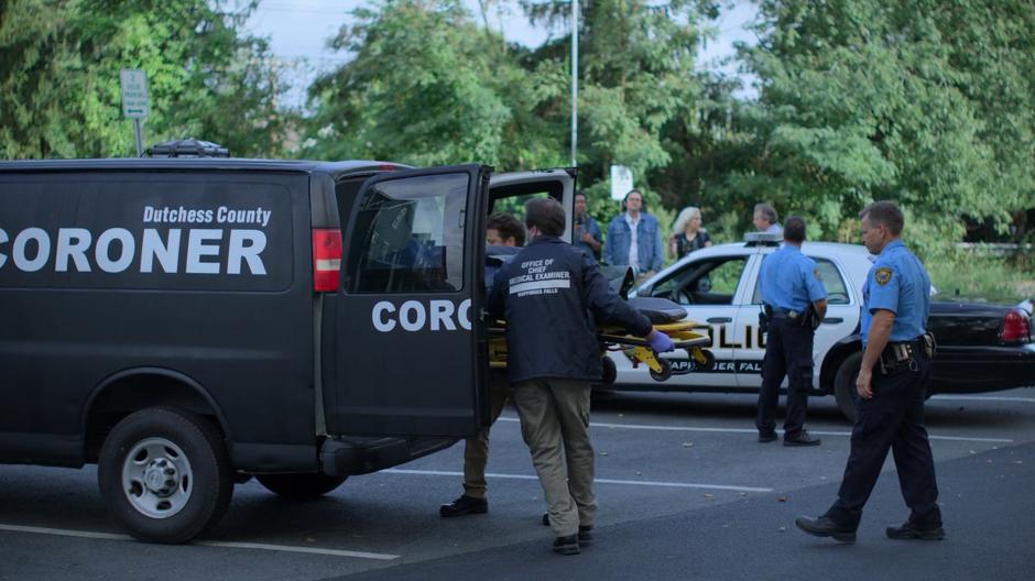 The medical examiners loads the body into the back of their van.