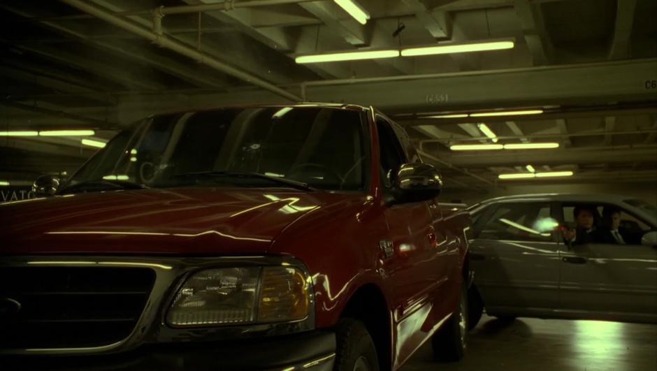 A goon fires at Sydney's truck from his car after blocking her escape.