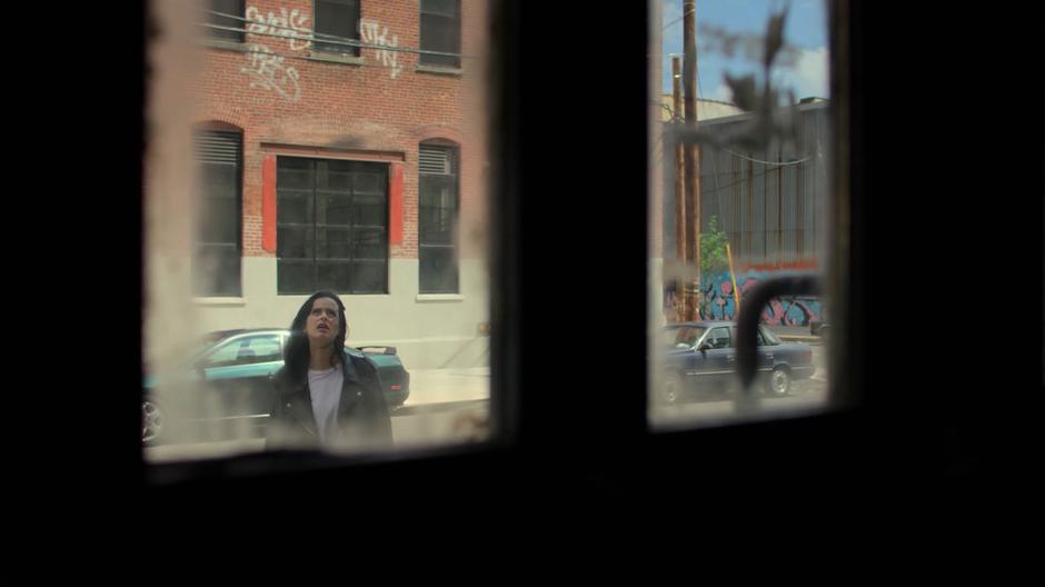 Jessica looks up at the sketchy building while standing outside.