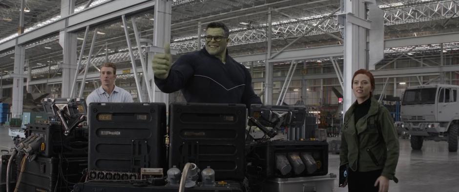 Bruce gives a giant thumbs up while standing behind the control panel with Steve and Natasha before the test.