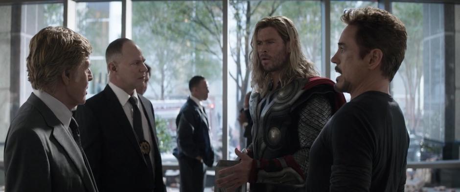 Past Tony talks to Alexander Pierce who is staring at Thor.