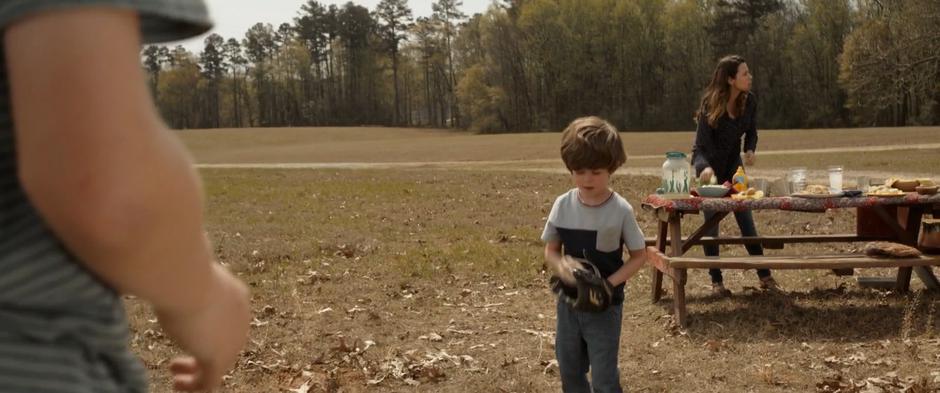 Laura Barton prepare the picnic table while Nathaniel and Cooper play catch.