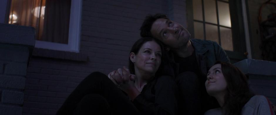 Hope, Scott, and Cassie sit together outside watching the fireworks.