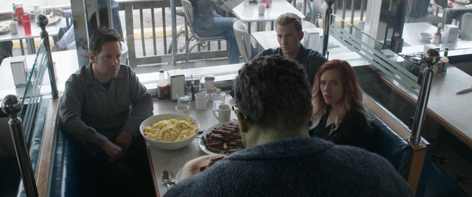 Scott, Steve, and Natasha look up at half-Hulked Bruce as he eats a massive meal.