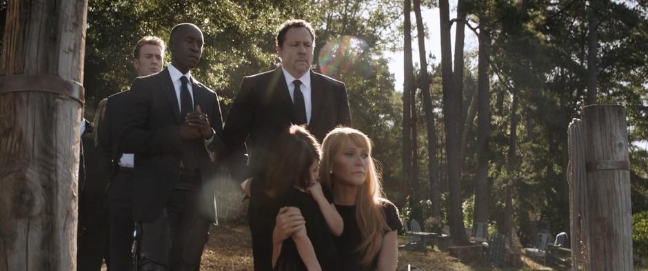 Pepper holds Morgan while Steve, Rhodes, and Happy stand behind them during Tony's funeral.