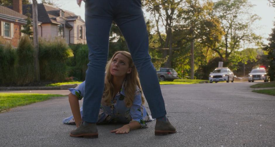 Darren stands over Emily in the street while police cars approach with lights flashing.