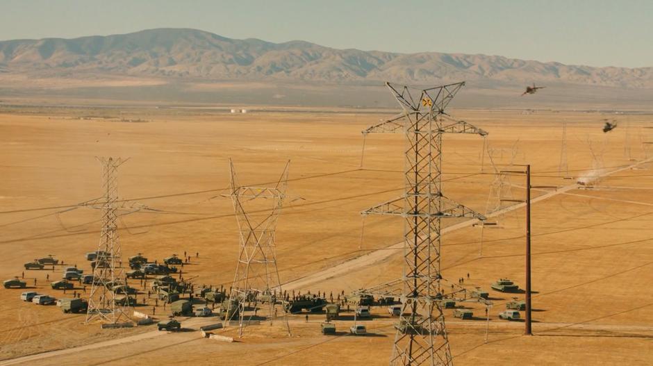 A huge military roadblock stands in the road in front of Dropkick and Shatter beneath some power lines.