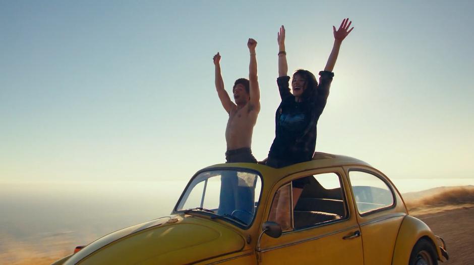 Memo and Charlie stand up through the sunroof with their hands in the air while Bumblebee drives himself.