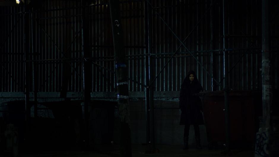 Jessica watches Trish's apartment from the shadows across the street.