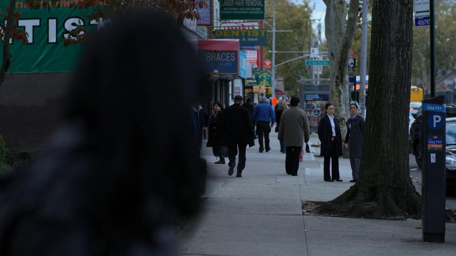 Jessica looks back down the block to see detectives Imada and Defford watching her.