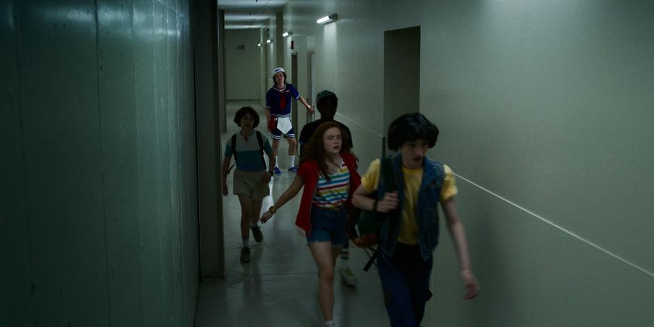 Steve watches Will, Lucas, Max, and Mike head down the back hallway towards the cinema.