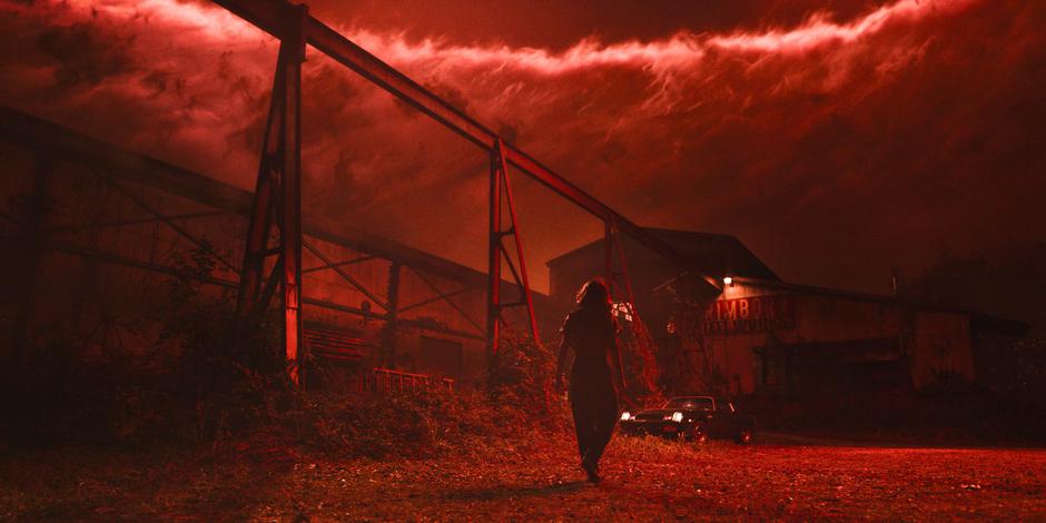 Eleven walks towards the steel works in her vision and tries to read the sign which is illuminated by a red light.