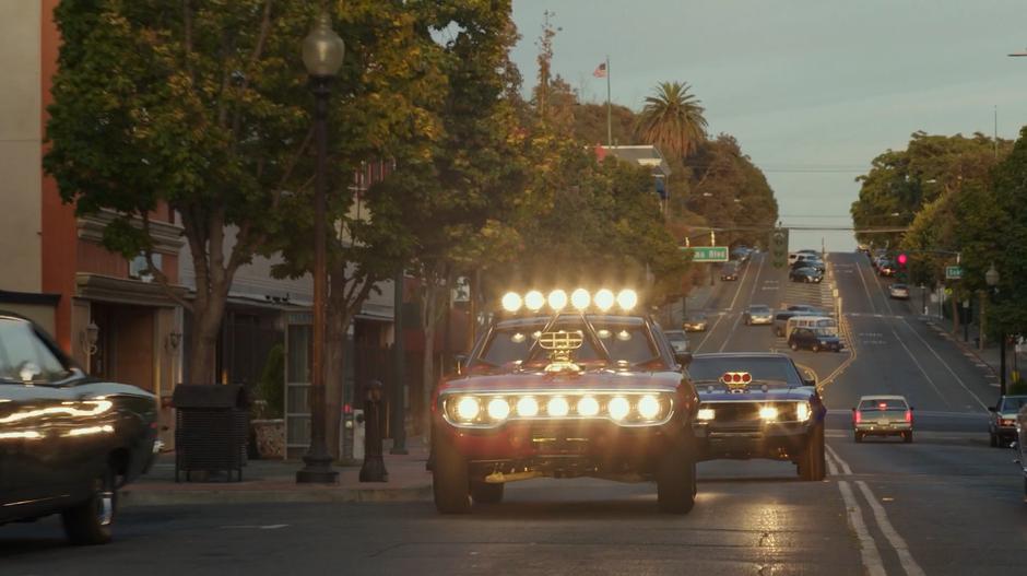 Shatter and Dropkick drive down the road through town.