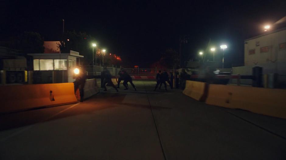 Soldiers jump to the side as Bumblebee races towards the gate.