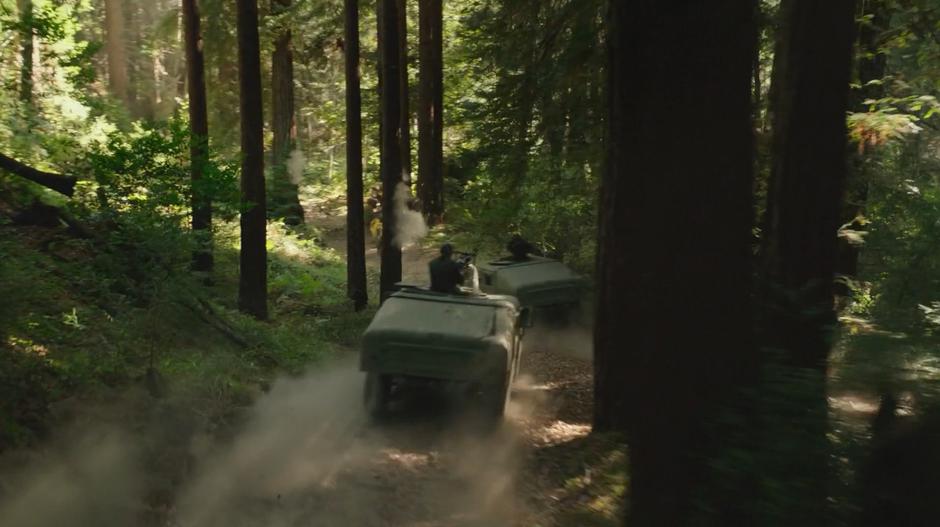 Two Humvees chase Bumblebee down a narrow dirt road.