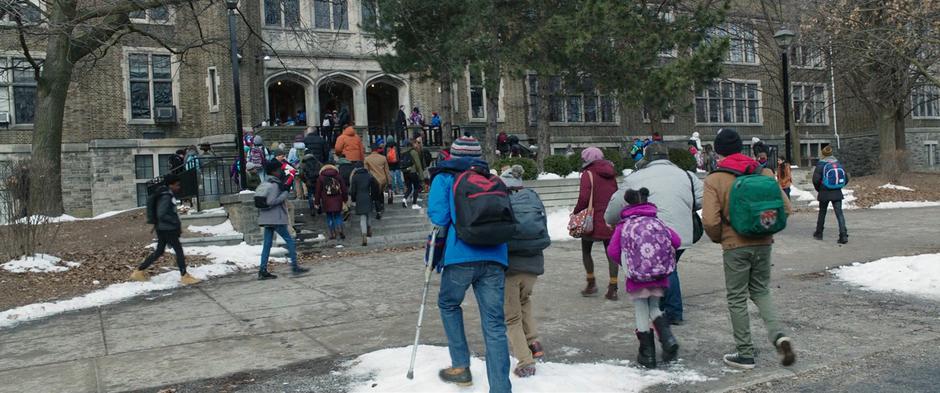 Freddy, Eugene, Mary, Darla, Pedro, and Billy walk across the sidewalk towards their school.