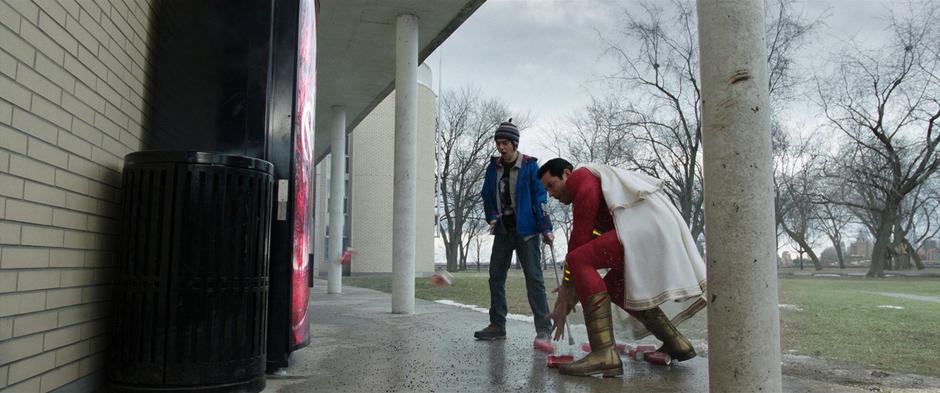 Freddy watches excitedly while Billy leans down to pick up some cans of soda that are flying out of the machine.