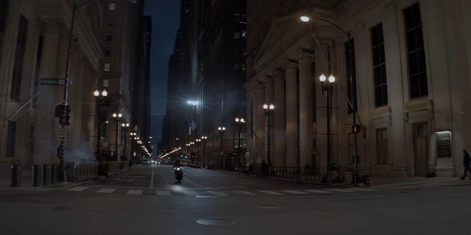 Kate rides her motorcycle up to the Wayne Enterprises building.