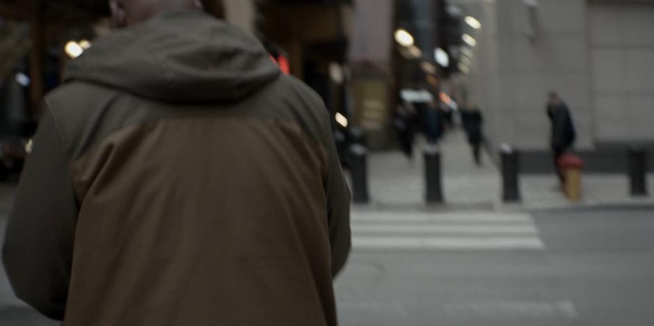 A man crosses the street while reading the newspaper.