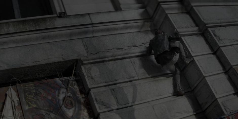 Kate climbs up the stone blocks to the second floor of the building.