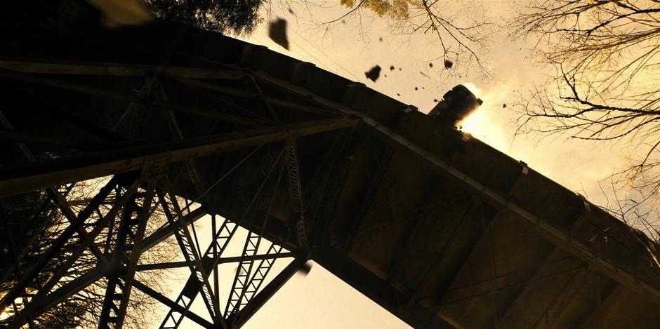 Debris falls from the bridge as the car hangs precariously over the edge.