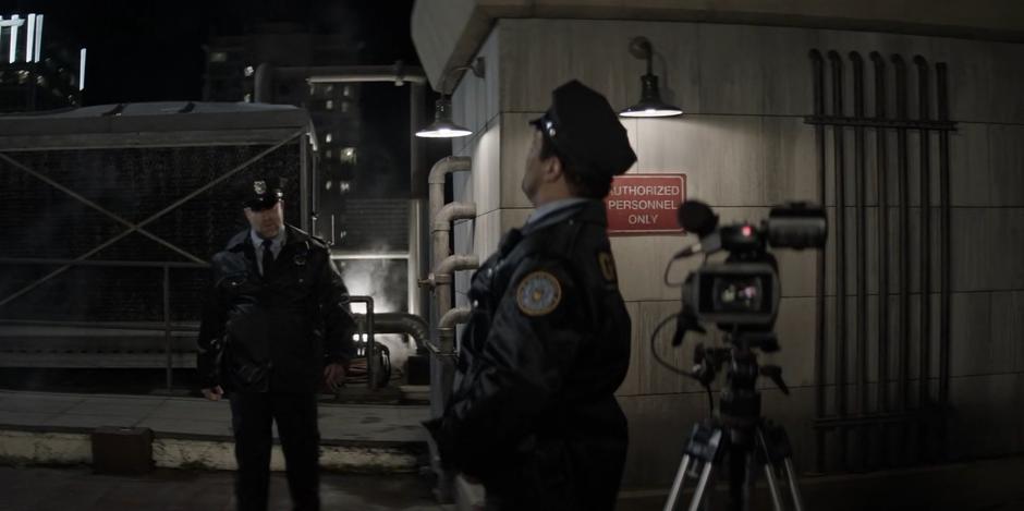 A police officer greets his colleague who is waiting by the camera for the shutoff.