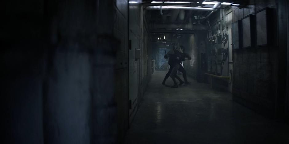 Kate fights with one of the masked members of Alice's gang in the basement hallway.