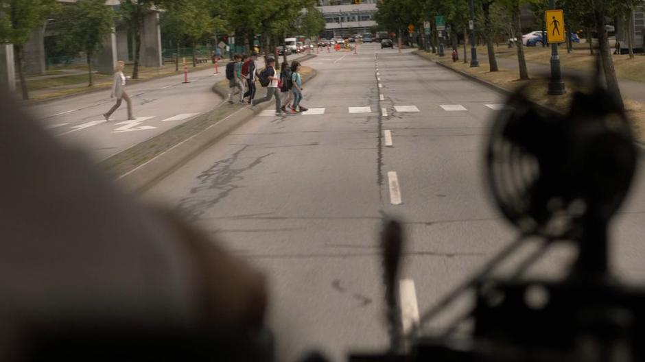 A group of kids cross the street in front of the runaway school bus.