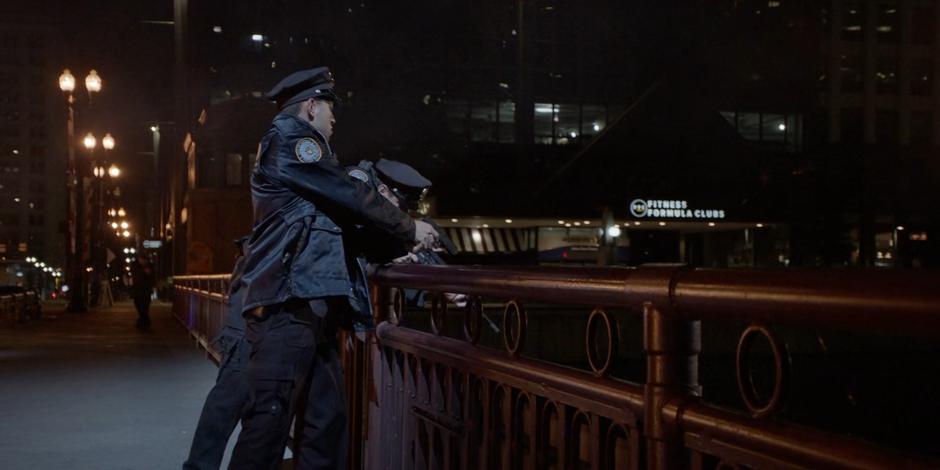 Two cops fire over the bridge railing at where the van went into the water.