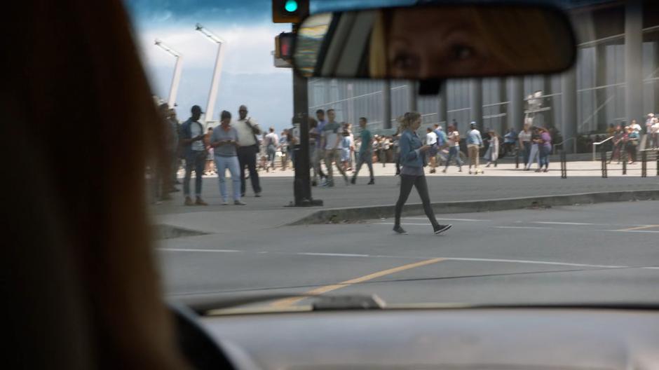 A pedestrian crossing against the light is visible through the windshield of an oncoming car.