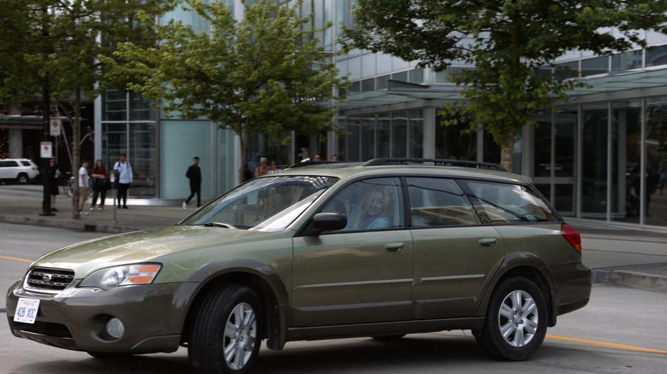 A woman driving down the street swerves to a stop after narrowly avoiding the pedestriant.