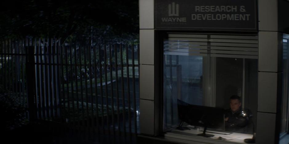 A security guard watches Tommy Elliot's advertisement while sitting in the gate booth.