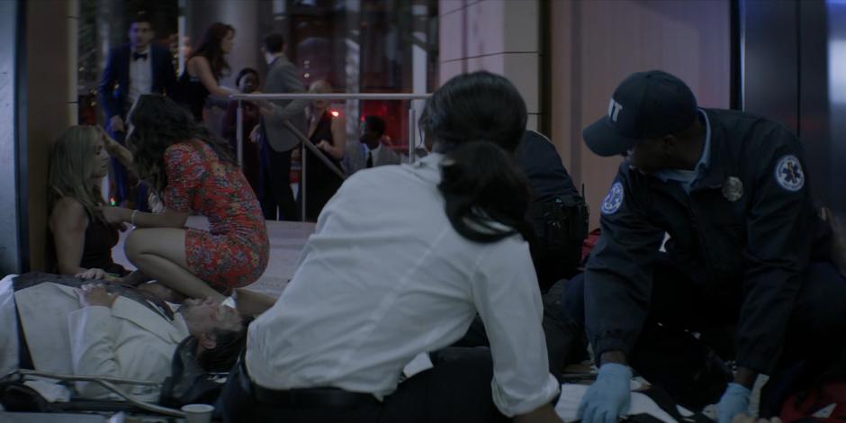 Sophie and the paramedic look over at Mary as she examines one of the survivors.