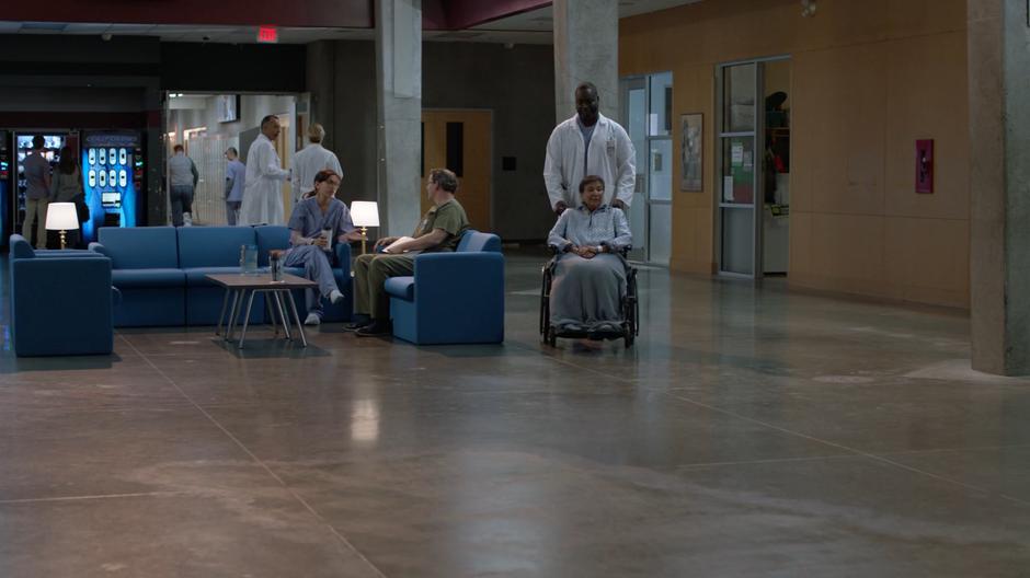 Dr. Stern pushes a patient in a wheelchair through the hospital.