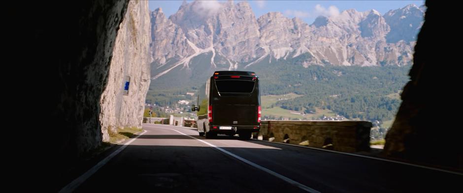 The tour bus drives out of the arch and along hte cliffside road.