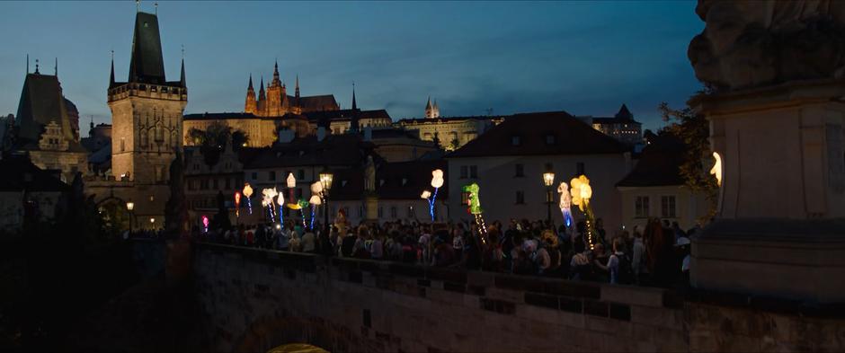 Revelers walk along hte top of the bridge at dusk.