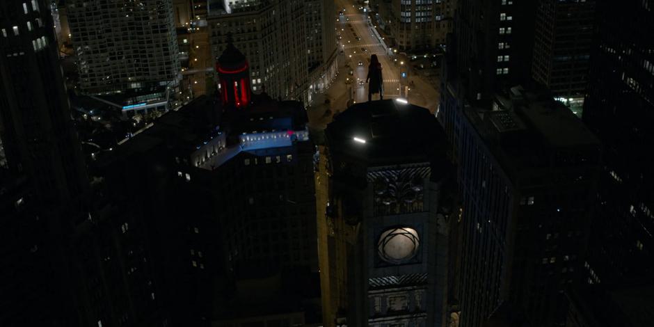 Kate stands on top of the building as Batwoman looking down on the city.