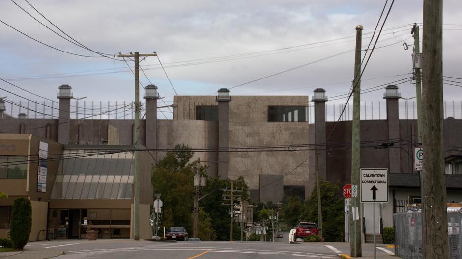 A massive prison wall rises above the town in the distance.