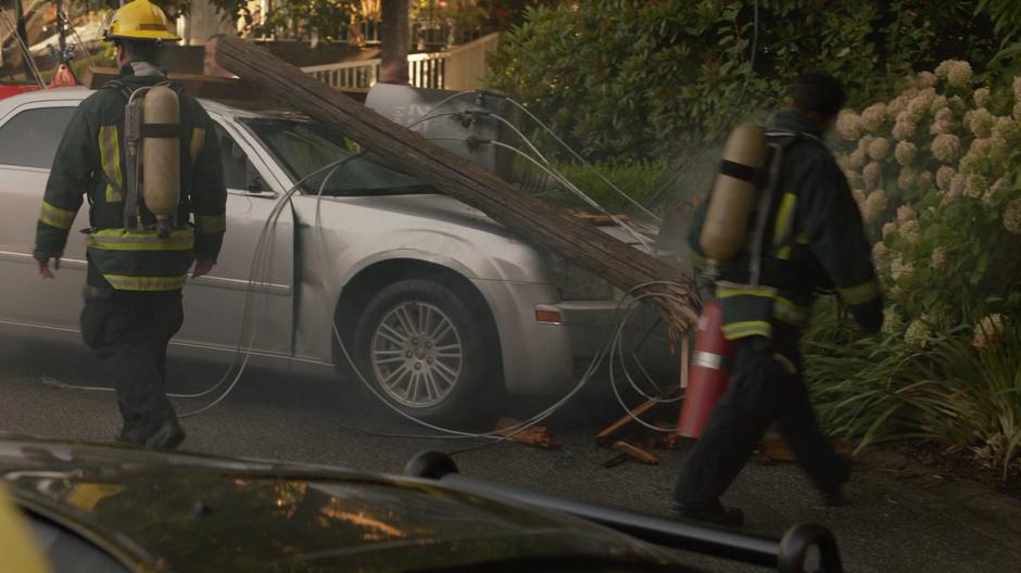 FIre fighters finish putting out the fire on Elena Torres' car which was crushed by an electrical pole.