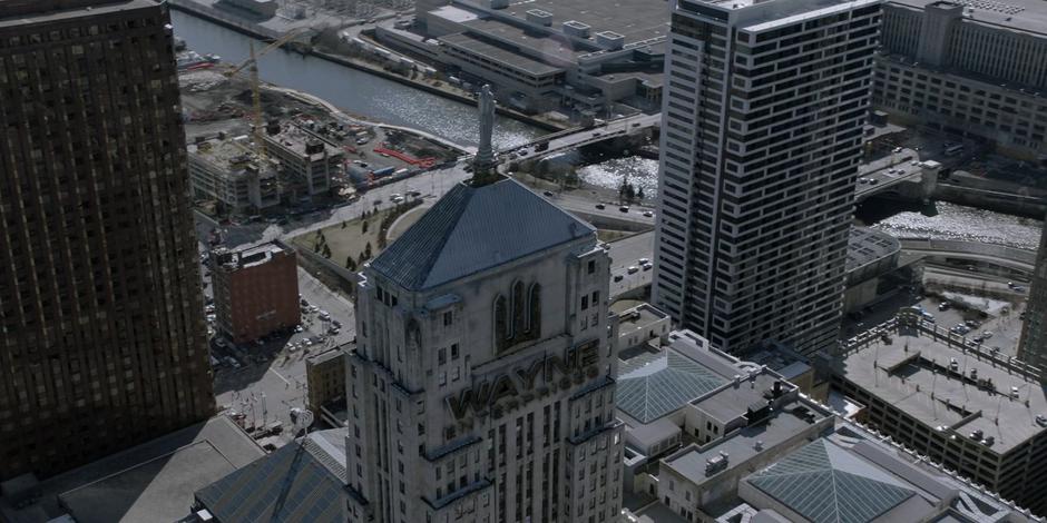 Aerial establishing shot of the Wayne Enterprises tower during the daytime with the river in the background.