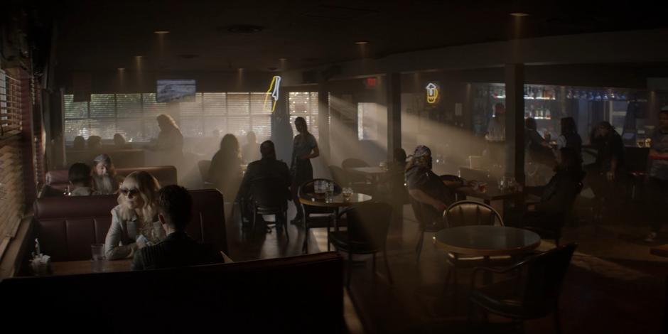 Alice sits at the table with Kate in a corner of the bar.