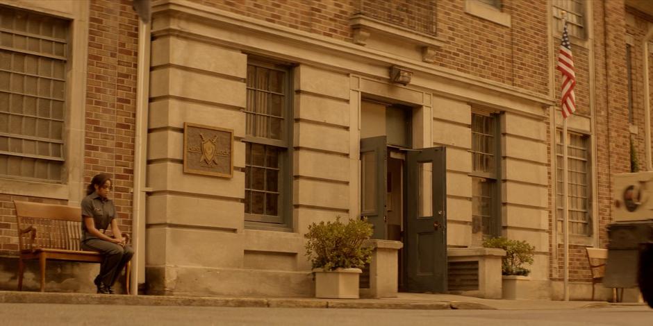 Sophie sits nervously on the bench outside the building while waiting for her hearing.