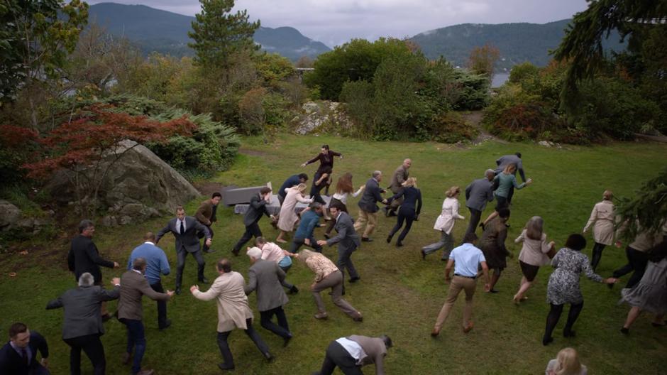 Lena tries to keep her balance and the assembled reporters flee as the Earth shakes.