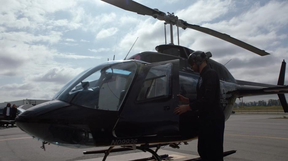 The helicopter pilot closes the door as Andrea helps Russell out of her car.