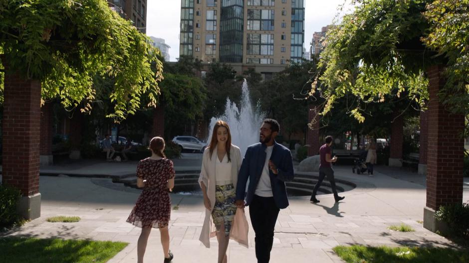 Andrea and Russell hold hands while walking through the park.