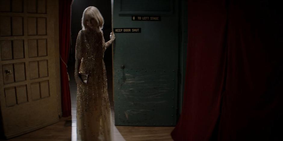 Alice closes the door to the backstage room where Mary is taking care of her mother.