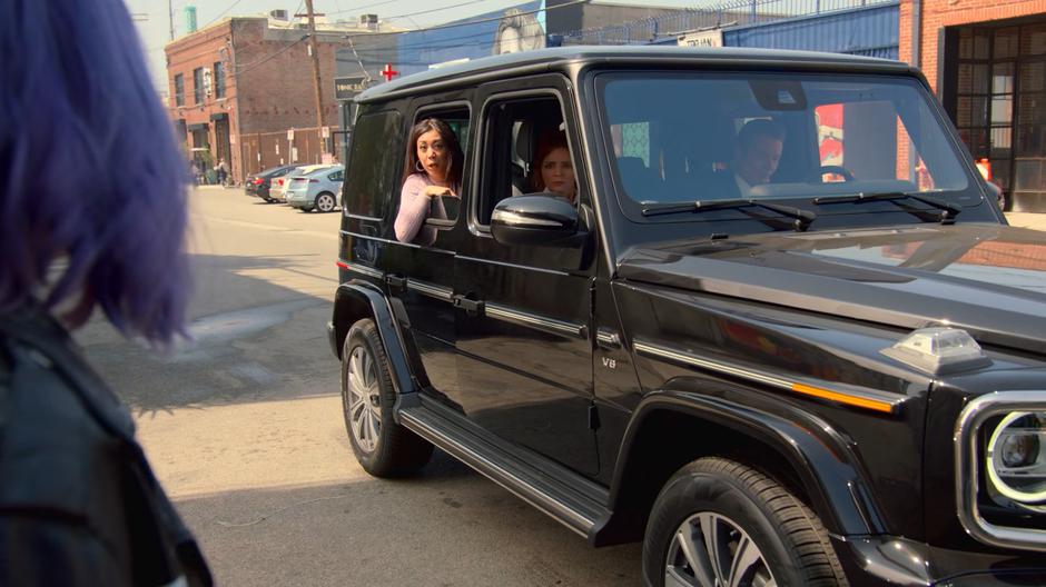 The Daughter pokes her head out of the car window while riding up in the car with the Wife and the Magistrate.