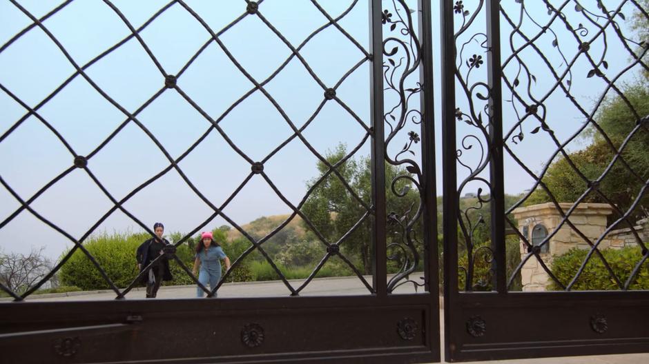 Xavin and Molly run across the street to the gate leading to the house.